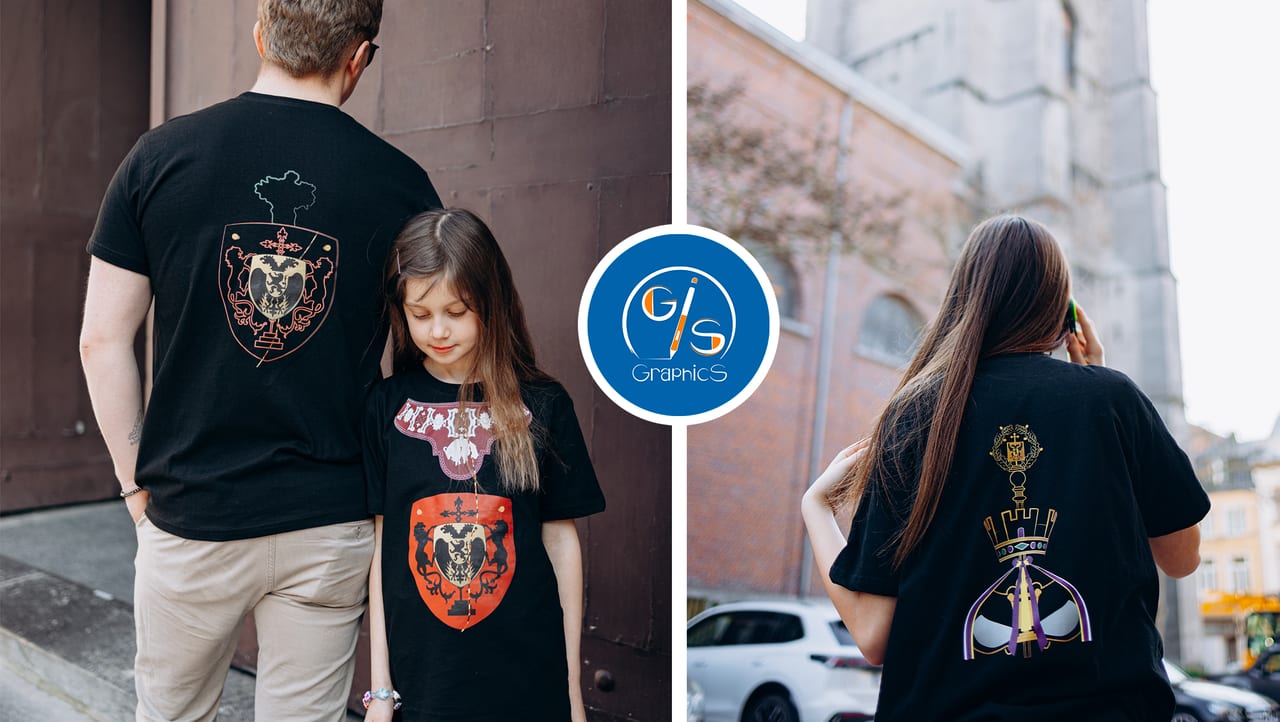 Un père et sa fille, puis une jeune femme, vus de dos dans les rues d’Ath, portent des t-shirts noirs illustrés des géants.